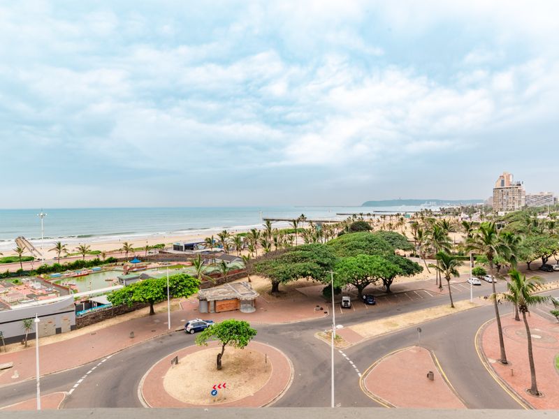 Elevated coastal view overlooking the beach, promenade, public park, and surrounding urban infrastructure.