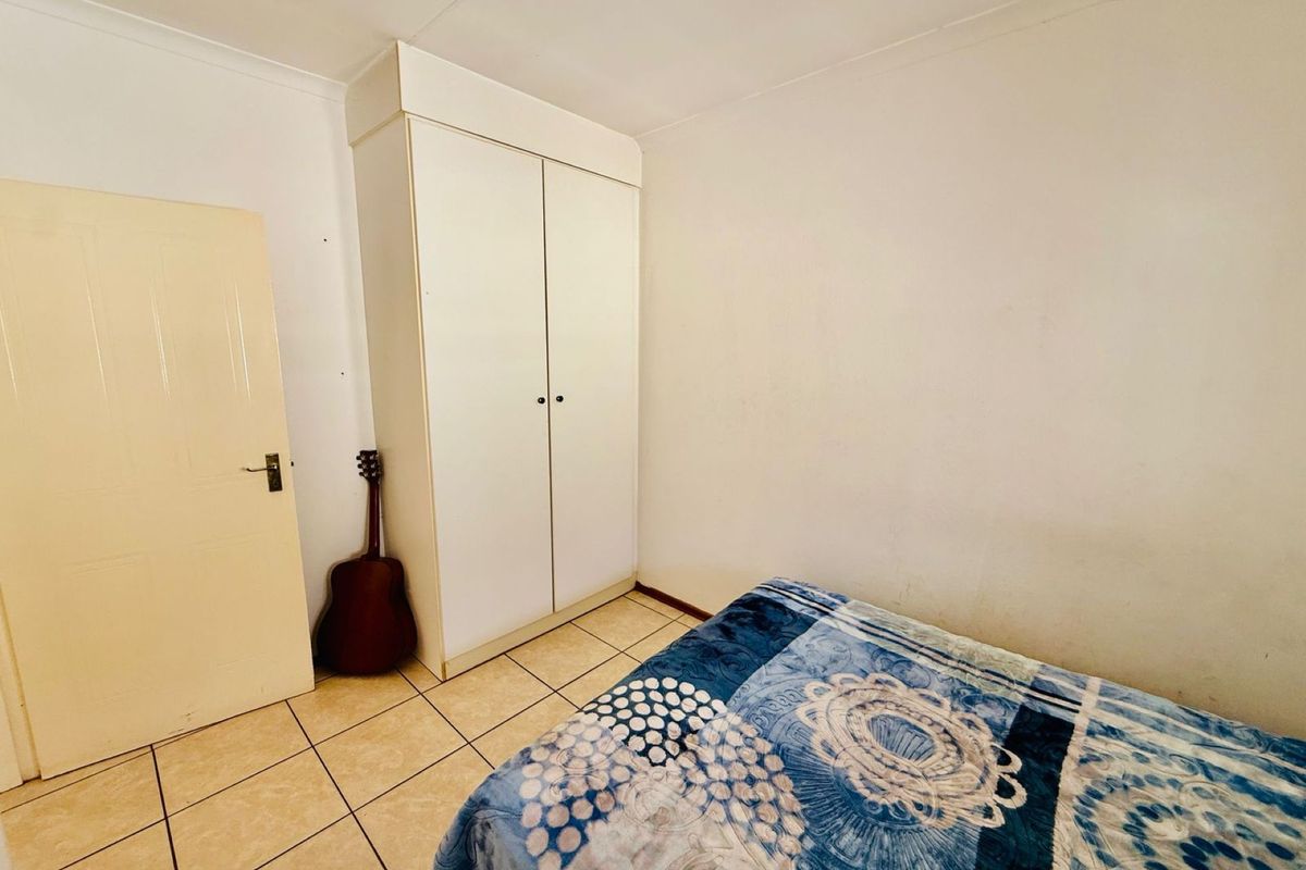 A bedroom featuring tiled flooring and a built-in white wardrobe.