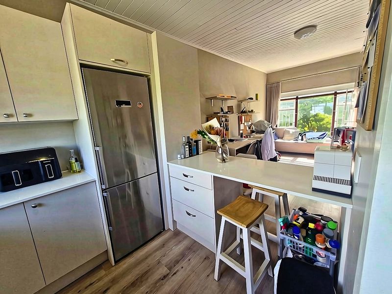 Open plan kitchen and living area featuring modern cabinetry, a breakfast bar, and light wood-look flooring, creating a functional and bright living space.