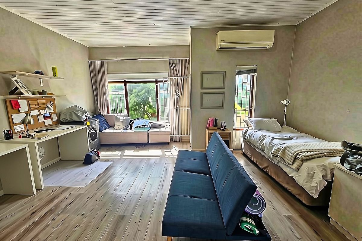 A bedroom featuring timber-look flooring, a built-in desk, and an air conditioning unit, with a timber-slat ceiling and natural light.