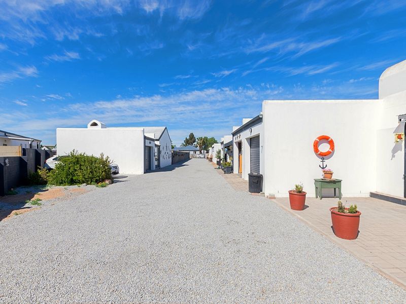 A view of the gravel driveway leading to multiple garage units with paved access paths and boundary walls.
