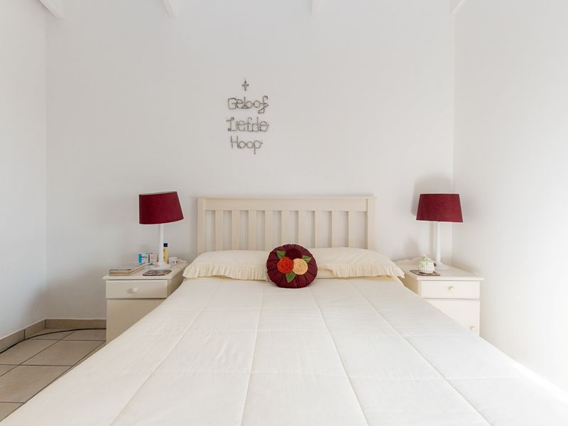 A neutrally decorated bedroom featuring tiled flooring and a vaulted ceiling, providing a clean and simple space.