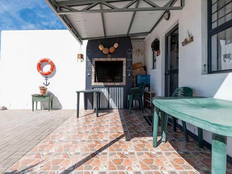 Covered outdoor patio featuring a built-in braai, tiled flooring, and direct access to the main dwelling.