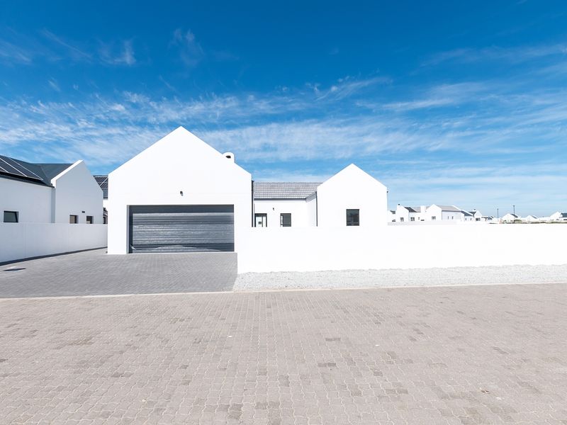 Modern single-story residence featuring a clean white facade, paved driveway, and integrated garage, situated in a well-maintained residential estate.