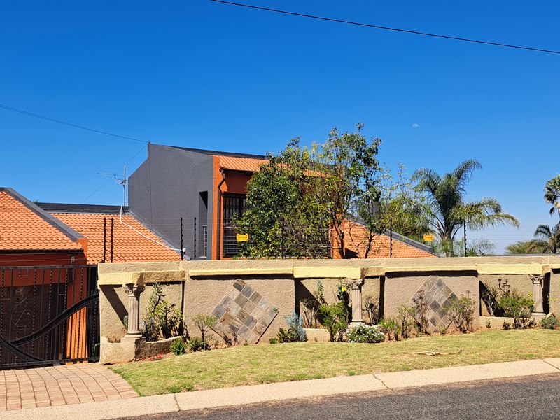 Front elevation of the cottage featuring a secure perimeter wall with electric fencing, tiled roof, and gated driveway access.
