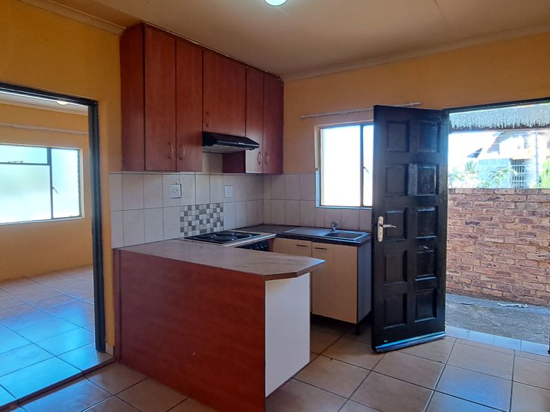 A functional kitchen featuring built-in cabinetry, a hob with extractor fan, and a breakfast counter, with direct access to an outdoor area.