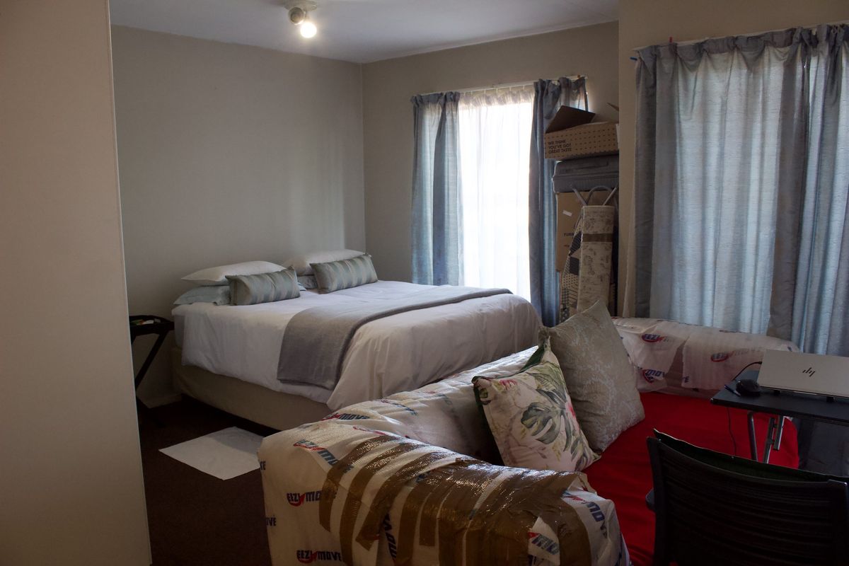 A functional bedroom space featuring neutral wall tones and window treatments, offering a comfortable layout for rest and relaxation.