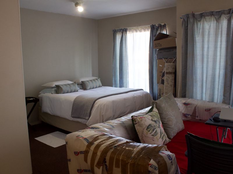 A functional bedroom space featuring neutral wall tones and window treatments, offering a comfortable layout for rest and relaxation.