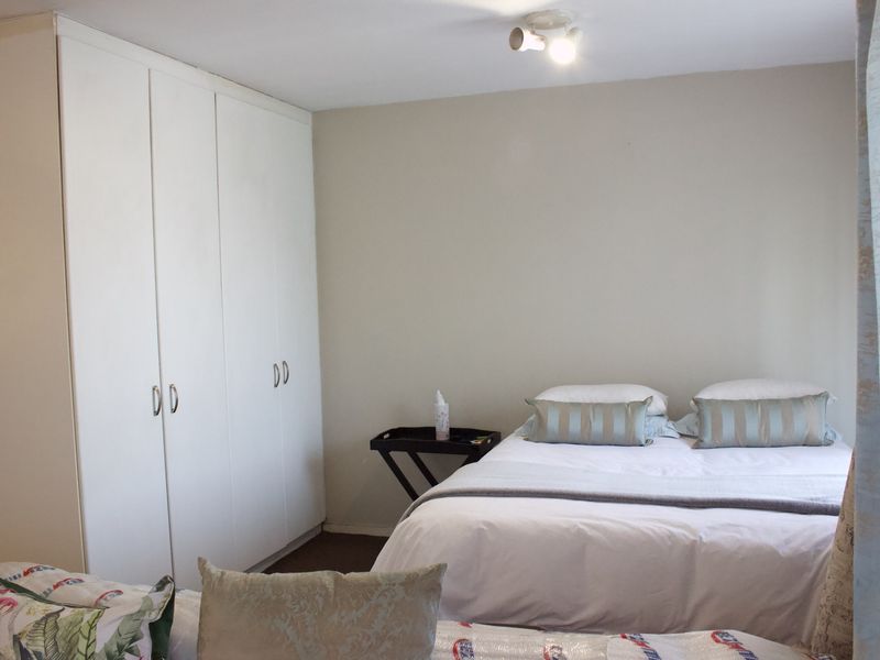 A bedroom featuring built-in white cupboards and neutral wall finishes, providing a functional and clean living space.