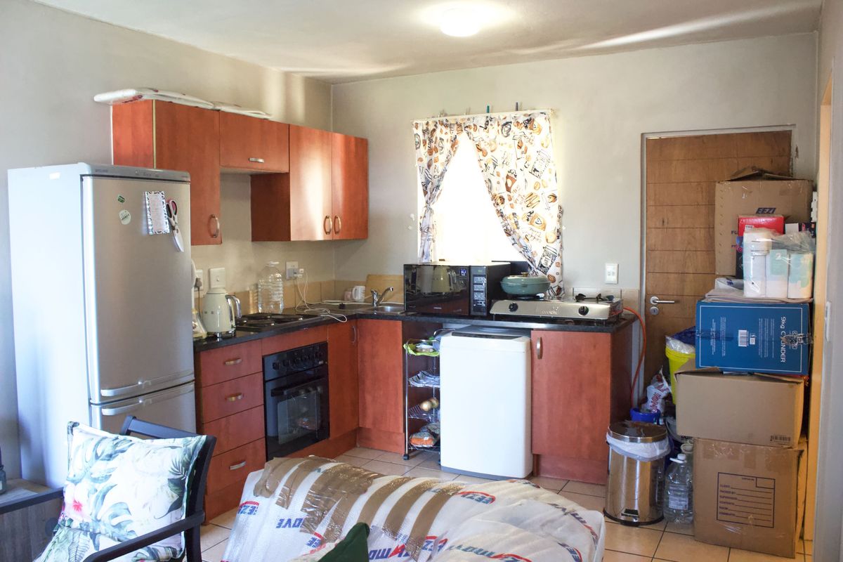 A compact kitchen featuring wood-tone cabinetry, laminate countertops, a built-in oven, and tiled flooring, offering a functional layout with potential for modernization.