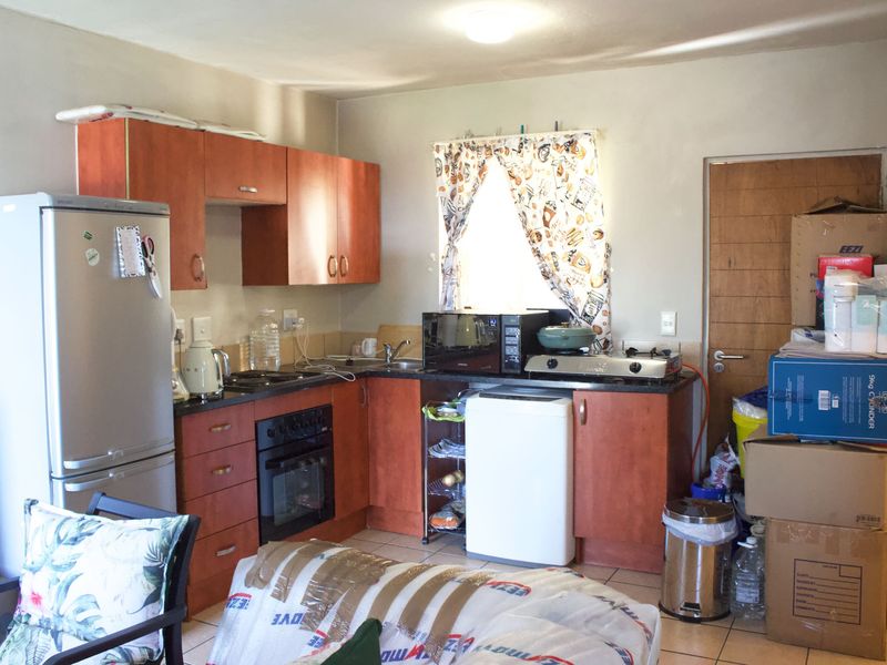 A compact kitchen featuring wood-tone cabinetry, laminate countertops, a built-in oven, and tiled flooring, offering a functional layout with potential for modernization.