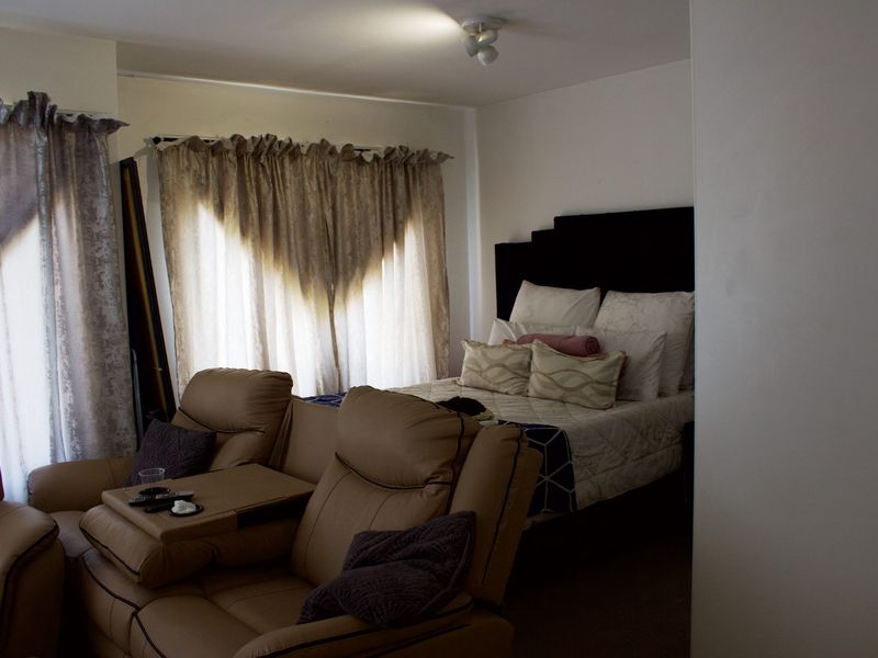 A bedroom featuring neutral wall finishes and natural light through window treatments.