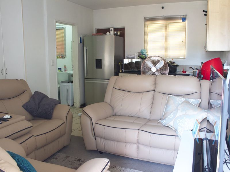 Open plan living area featuring a compact kitchen corner with built-in cabinetry and sink, providing a functional layout for apartment living.