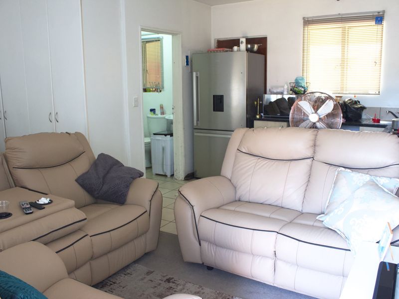 Open plan living area featuring built-in cupboards and tiled flooring, with an adjacent view into a bathroom space.