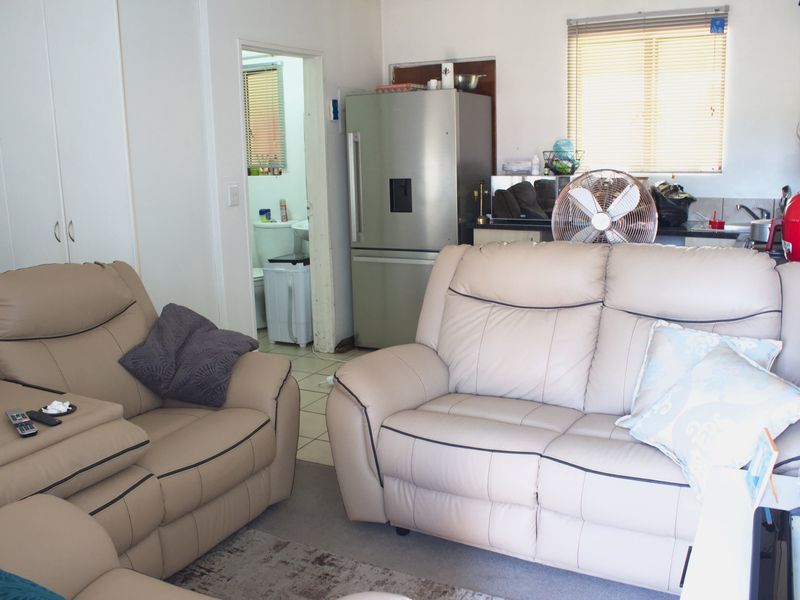 Open plan living area featuring tiled flooring, built-in storage cupboards, and venetian blinds, with direct access to an adjacent bathroom.