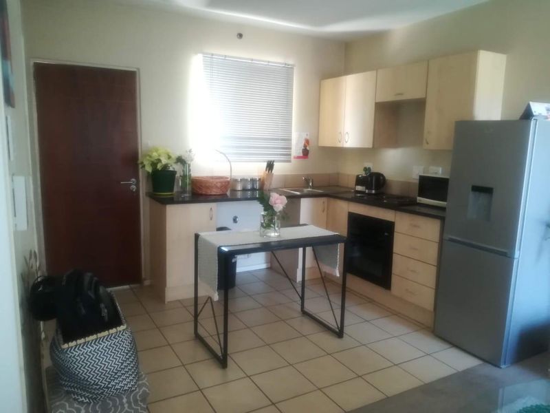 A functional kitchen featuring light-toned built-in cabinetry, dark countertops, a built-in oven, and tiled flooring, offering a practical layout for daily use.
