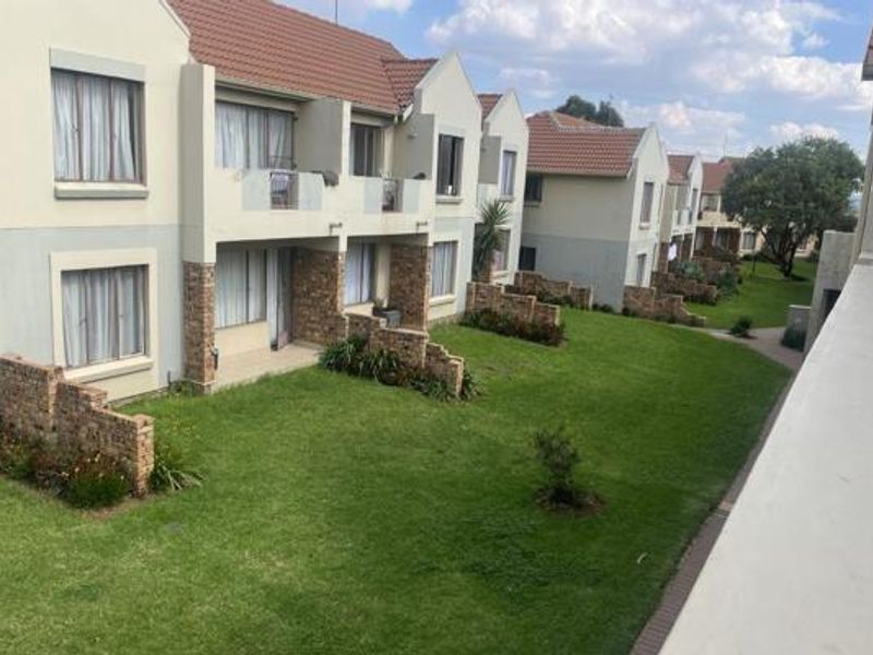 A view of the rear exterior of the apartment complex, featuring well-maintained lawns, brick-accented facades, and private balconies.