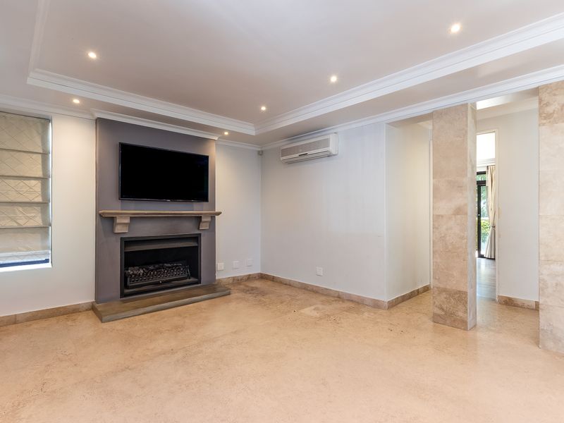 Spacious living room featuring a built-in fireplace with mantelpiece, stone-clad pillar, split-system air conditioning, and neutral travertine tile flooring.