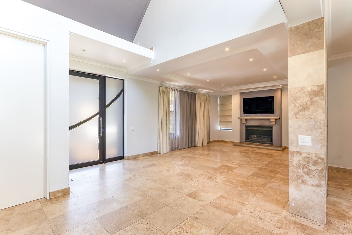 Spacious living room featuring high vaulted ceilings, travertine flooring, and a built-in fireplace, offering a bright and open atmosphere.