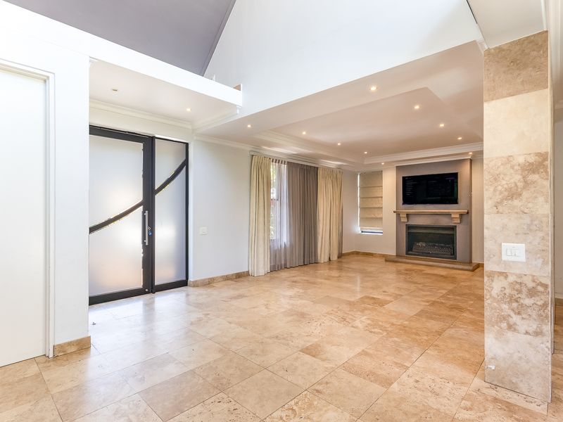 Spacious living room featuring high vaulted ceilings, travertine flooring, and a built-in fireplace, offering a bright and open atmosphere.
