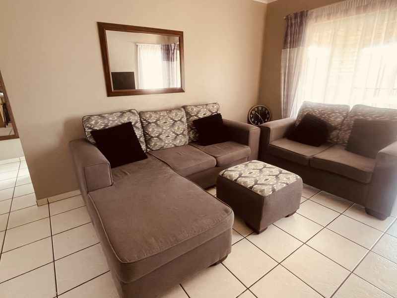 A living room featuring neutral wall tones, tiled flooring, and a sliding glass door providing natural light.