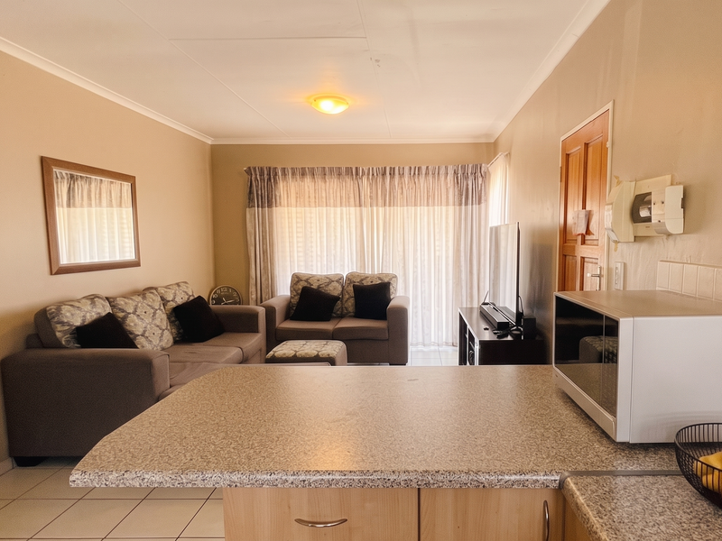 Open plan living area featuring a kitchen with laminate countertops and tiled flooring, leading to a lounge area with sliding door access.