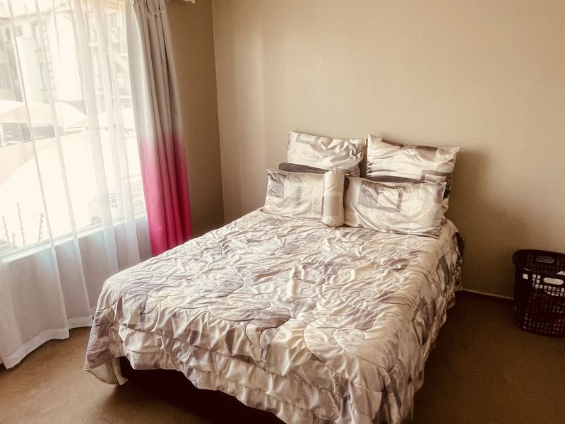 A standard bedroom featuring neutral wall tones, carpeted flooring, and a window with installed curtain hardware.