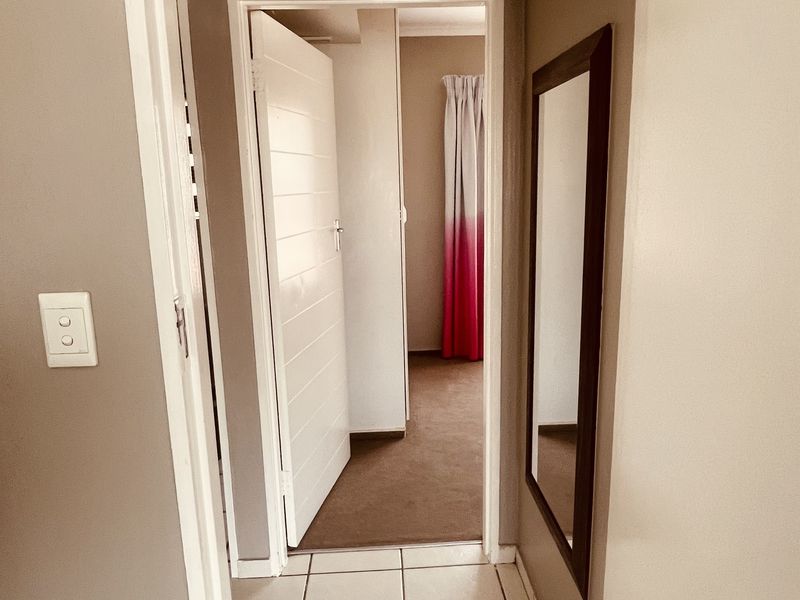 A functional hallway featuring tiled flooring and neutral wall tones, providing access to adjacent rooms within the apartment.