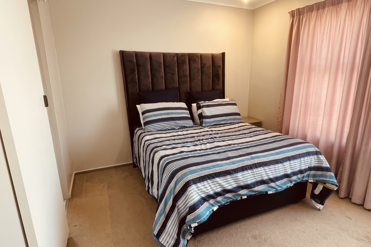 A well-proportioned bedroom featuring neutral wall finishes, carpeted flooring, and a built-in wardrobe, offering a comfortable and functional living space.