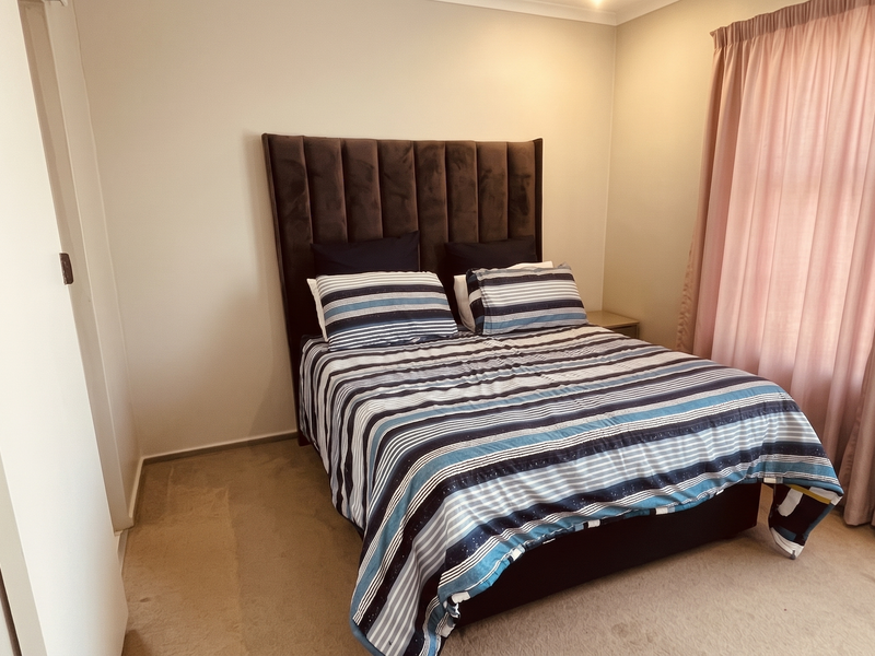 A well-proportioned bedroom featuring neutral wall finishes, carpeted flooring, and a built-in wardrobe, offering a comfortable and functional living space.