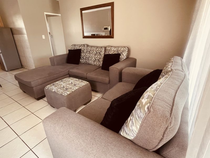 Open-plan living area featuring neutral wall tones and tiled flooring, seamlessly connecting to a functional kitchen space.