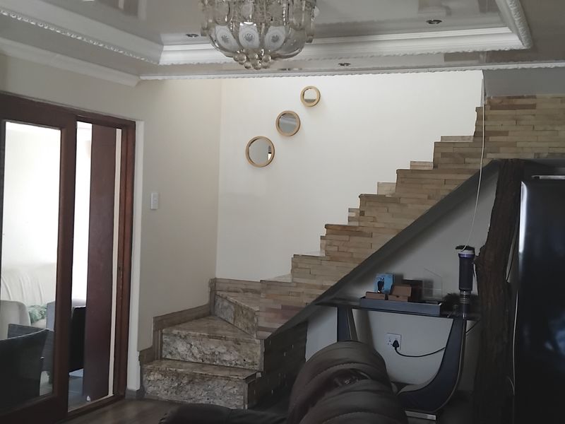 Living area featuring a stone-clad staircase with granite treads, a matching stone fireplace surround, and decorative ceiling molding.