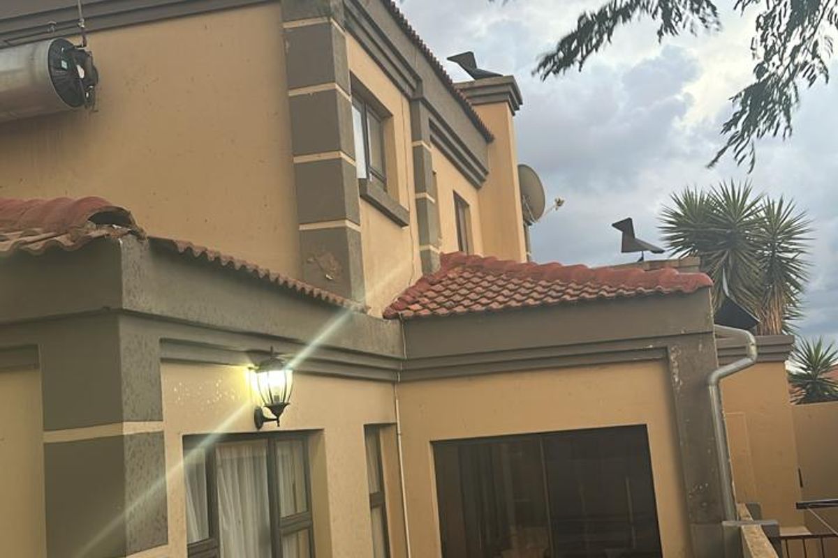 Rear exterior view of the townhouse featuring a paved patio area, sliding glass doors, and a solar water heating system installed on the roof.
