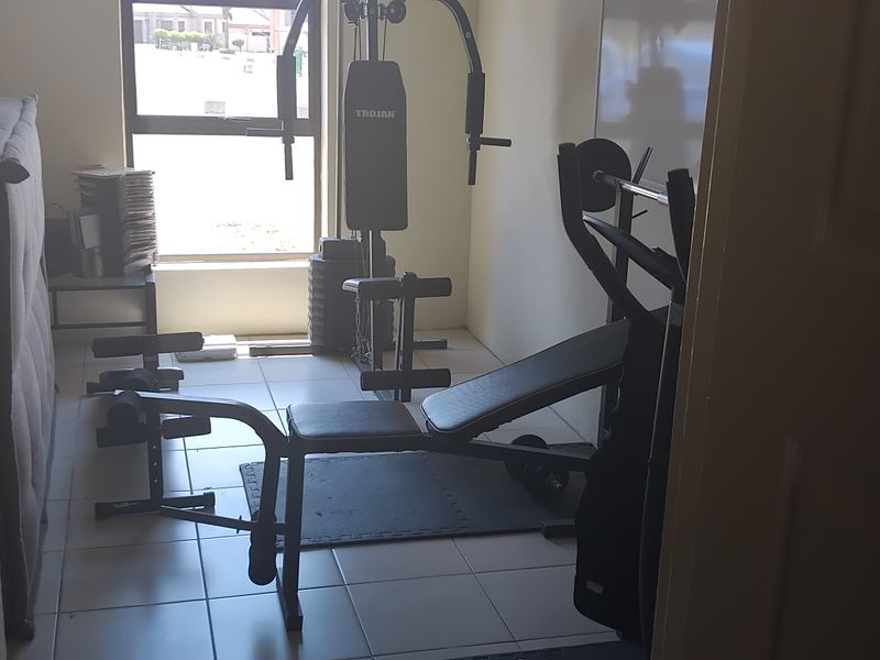 A small room currently utilized as a home gym, featuring tiled flooring and a large window providing natural light.