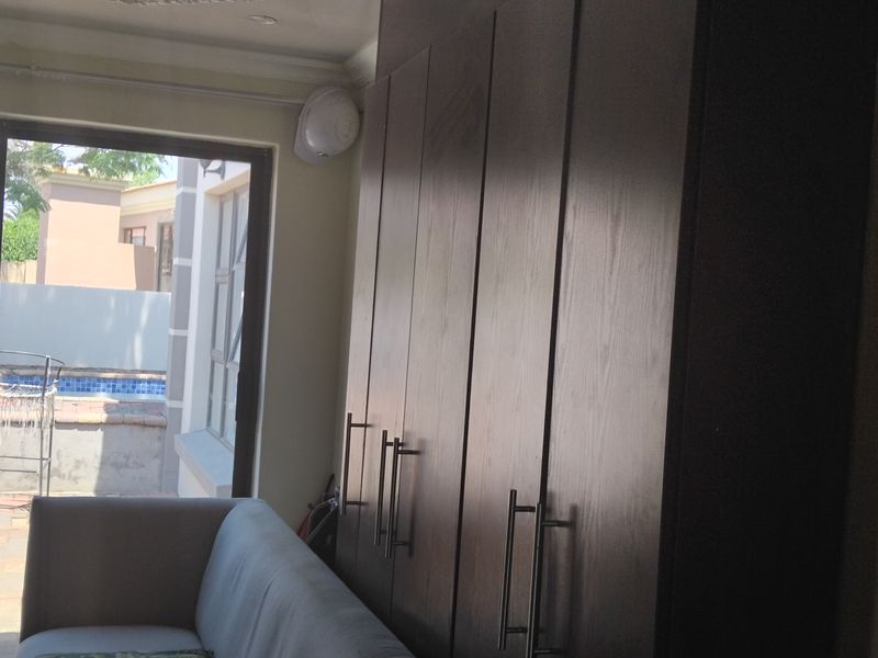 Living area featuring dark wood built-in cupboards and a sliding glass door providing access to the outdoor patio and pool area.