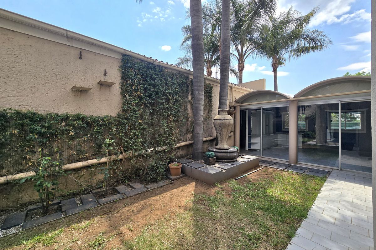 A private rear garden area featuring a stone fountain, tiled pathway, and large sliding glass doors providing access to the interior living space.