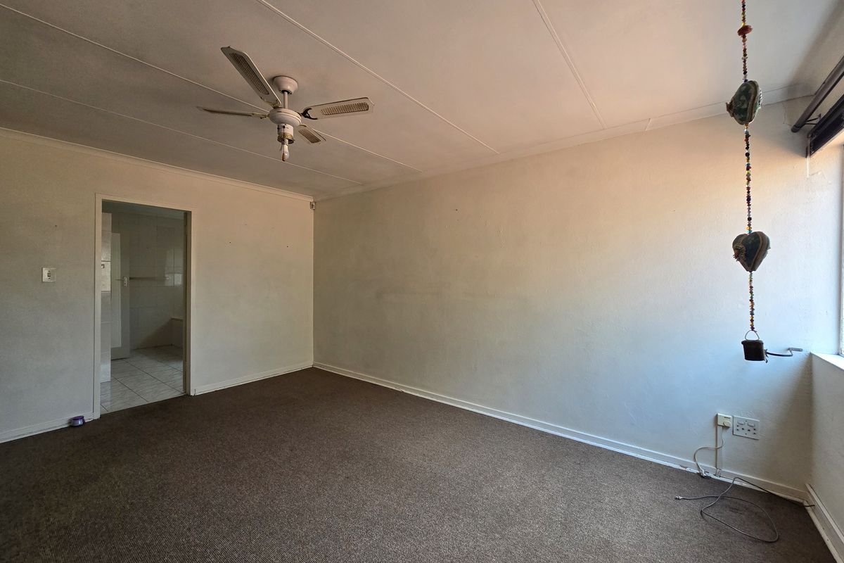 An empty bedroom featuring a ceiling fan, carpeted flooring, and neutral wall finishes, offering a blank canvas for potential renovation or staging.