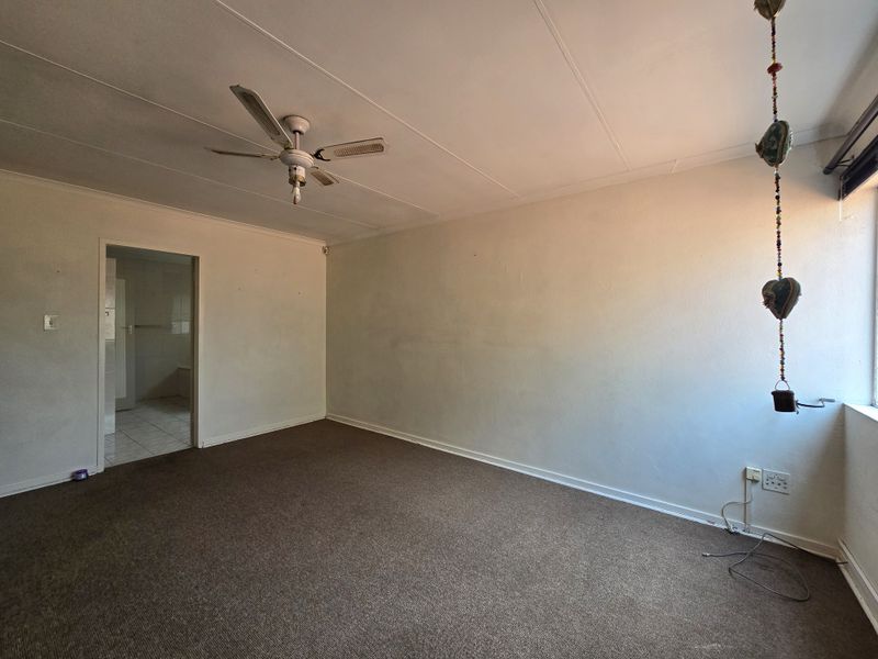 An empty bedroom featuring a ceiling fan, carpeted flooring, and neutral wall finishes, offering a blank canvas for potential renovation or staging.
