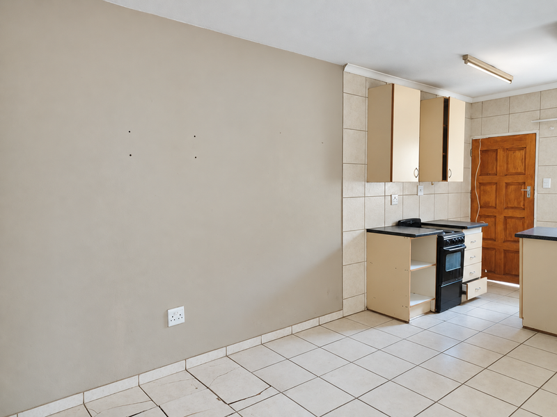 A dated kitchen area featuring tiled flooring, built-in cabinetry, and a freestanding oven, requiring cosmetic updates to modernize the space.