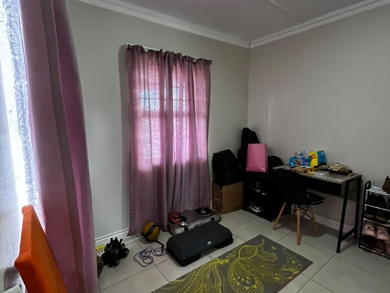 A functional bedroom space featuring neutral tiled flooring and coved ceilings, currently utilized as a multi-purpose room.