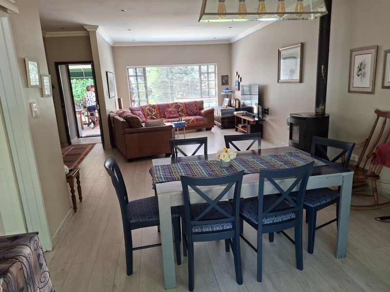 Spacious open-plan living and dining area featuring light laminate flooring, a wood-burning fireplace, and direct access to an outdoor patio.