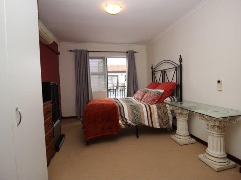 A bedroom featuring carpet flooring, a built-in wardrobe, a split-system air conditioner, and a sliding glass door leading to a balcony.