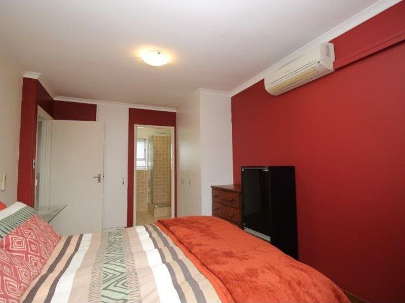 A bedroom featuring a built-in wardrobe, split-system air conditioning, and direct access to an en-suite bathroom.