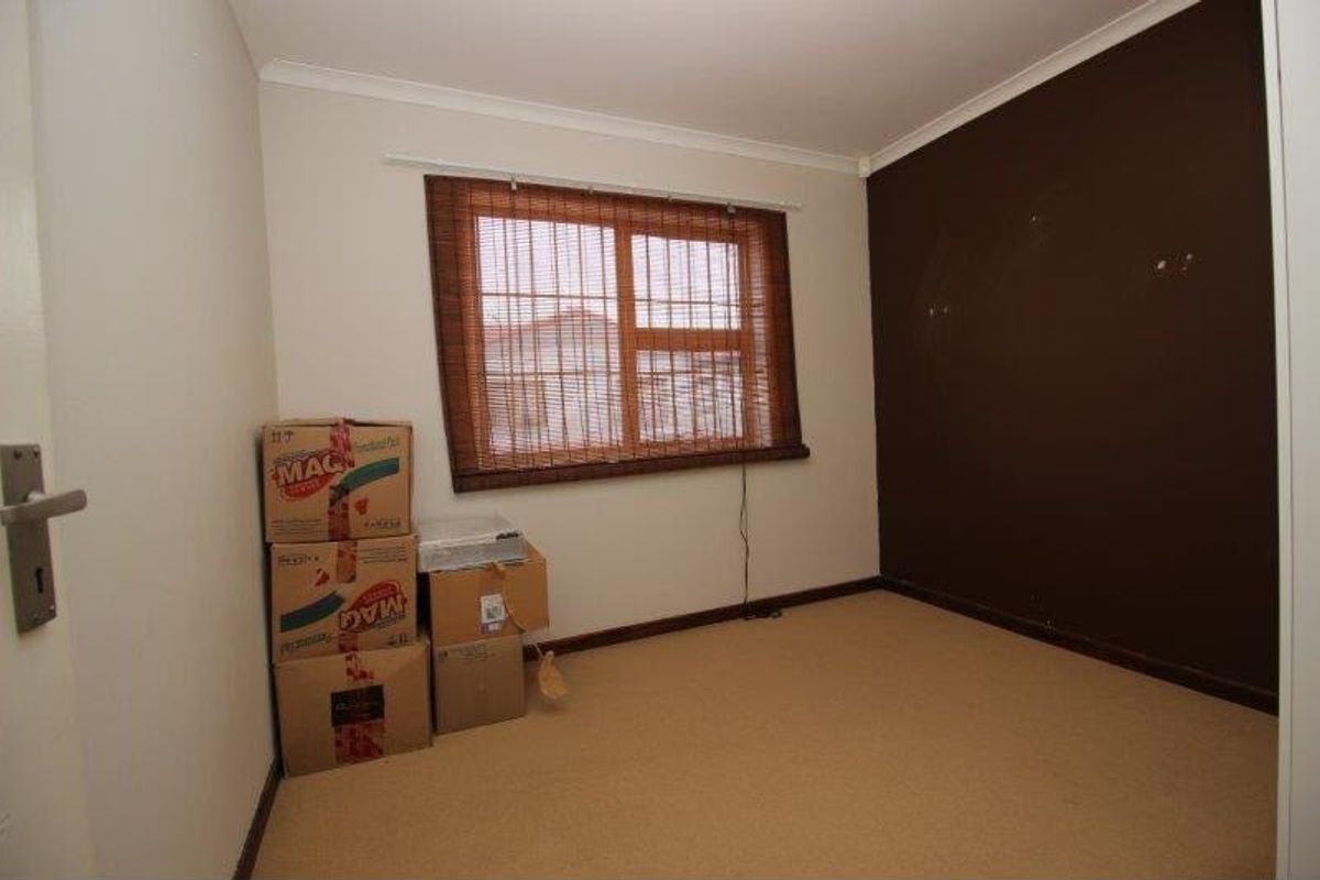 A vacant bedroom featuring carpeted flooring and a dark accent wall, presenting a blank canvas for potential interior updates.