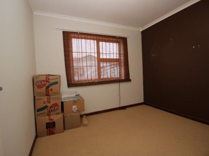 A vacant bedroom featuring carpeted flooring and a dark accent wall, presenting a blank canvas for potential interior updates.