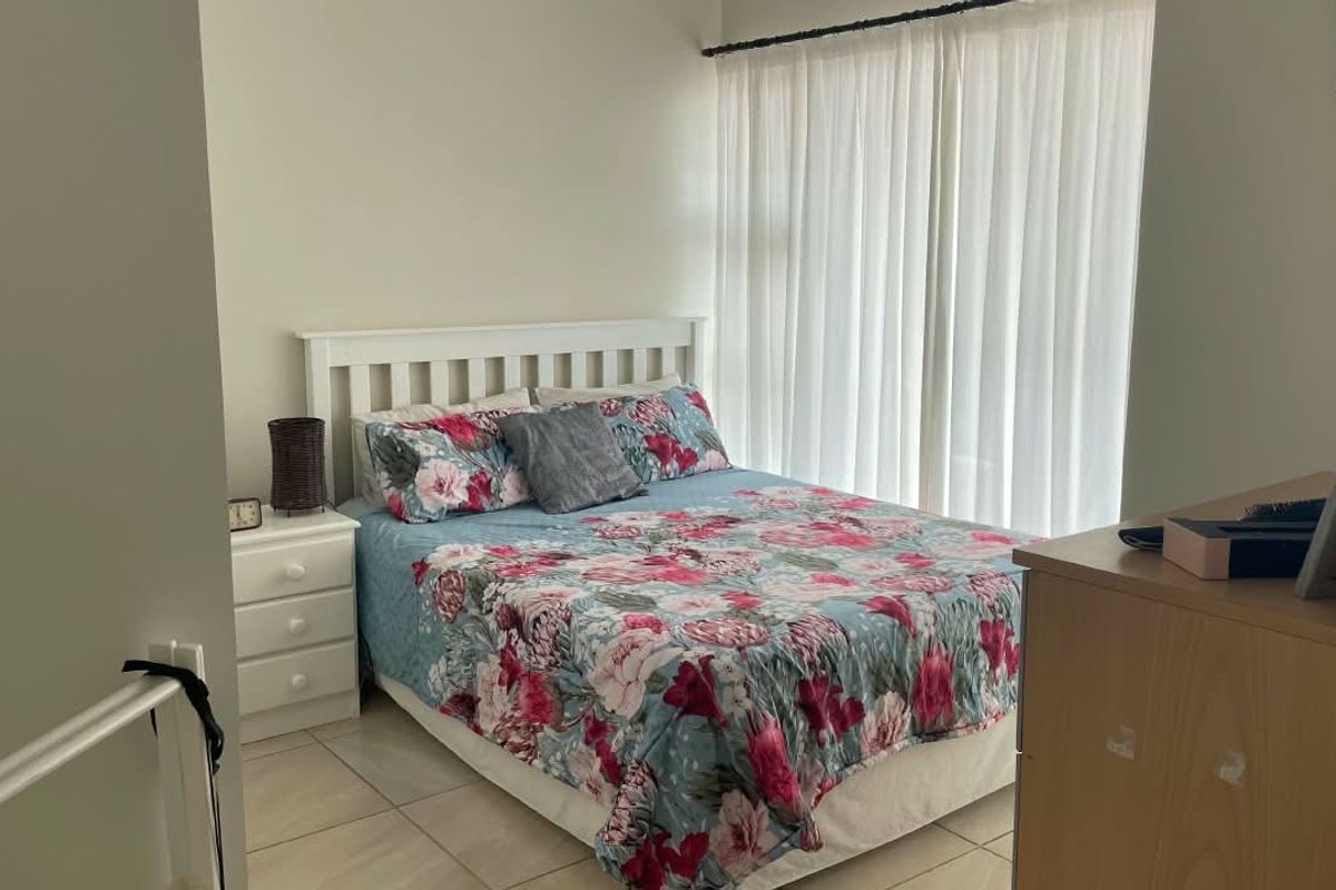 A functional bedroom featuring tiled flooring and a large window with curtain rails, providing a neutral base for personalization.