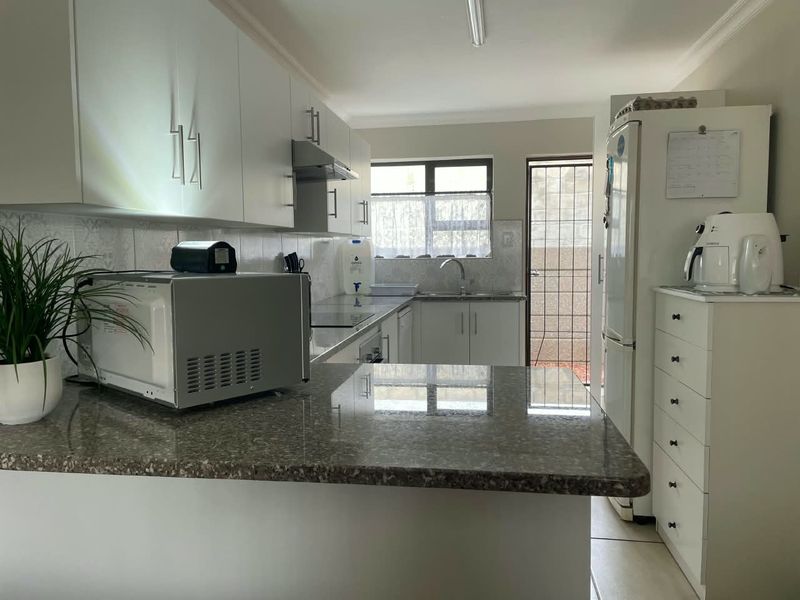 A functional kitchen featuring granite countertops, ample built-in cabinetry, and direct access to an exterior area through a secure door.