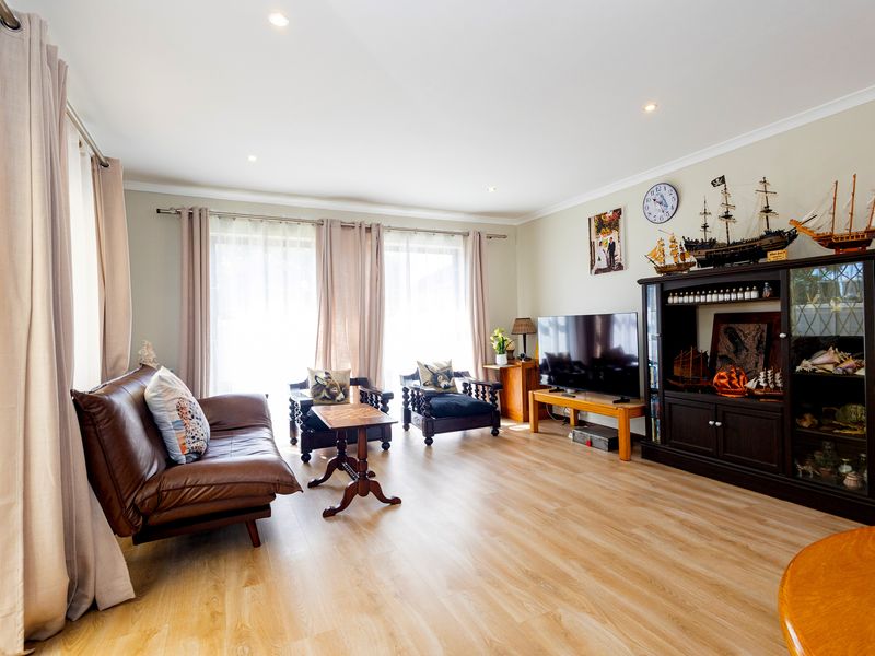 A bright and spacious living room featuring modern laminate flooring, recessed downlighting, and large sliding glass doors that provide ample natural light.