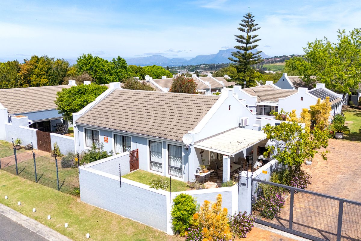 Aerial view of a townhouse complex featuring tiled roofs, private walled gardens, covered patios, and paved driveway access with secure perimeter fencing.