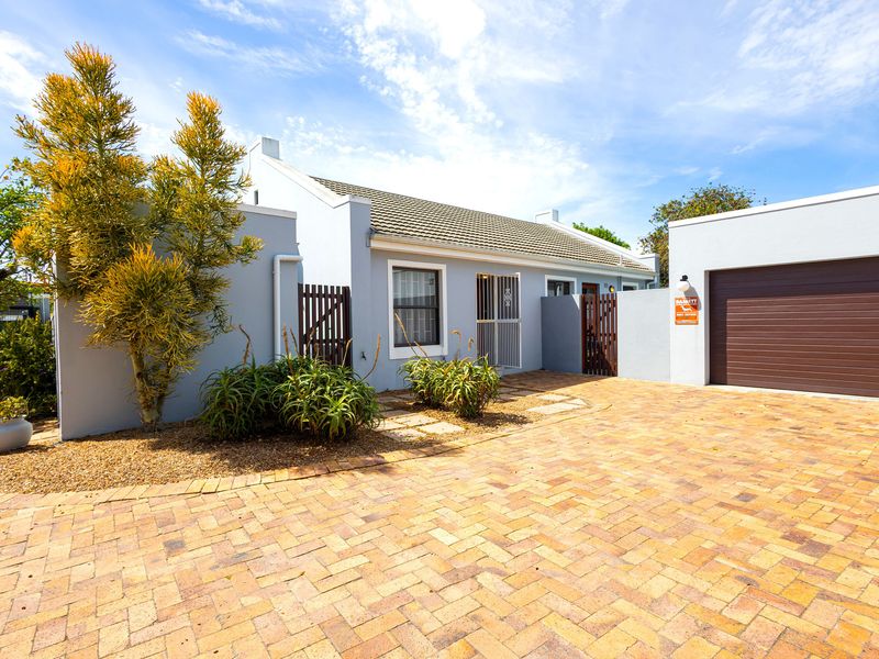 Front exterior view of a townhouse featuring a paved driveway, single garage, and secure gated entrance with well-maintained facade.